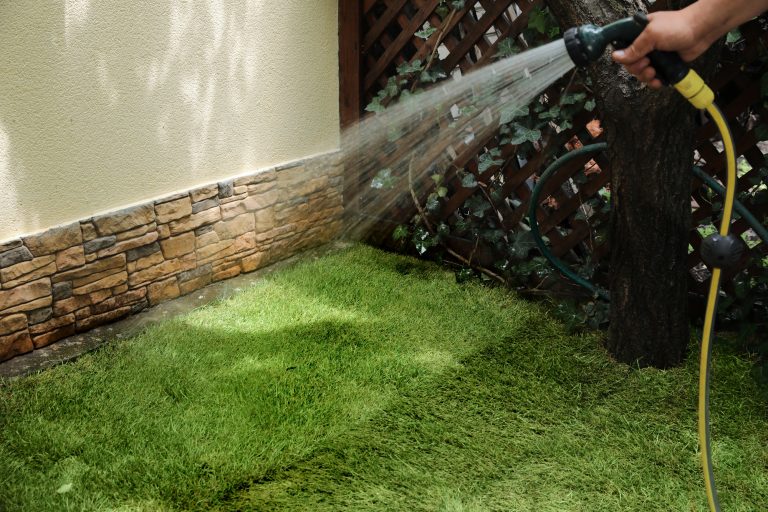 Man watering unrolled grass