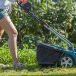 Woman cuts the lawn with an electric mower