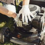 Man repairs lawnmover in a backyard