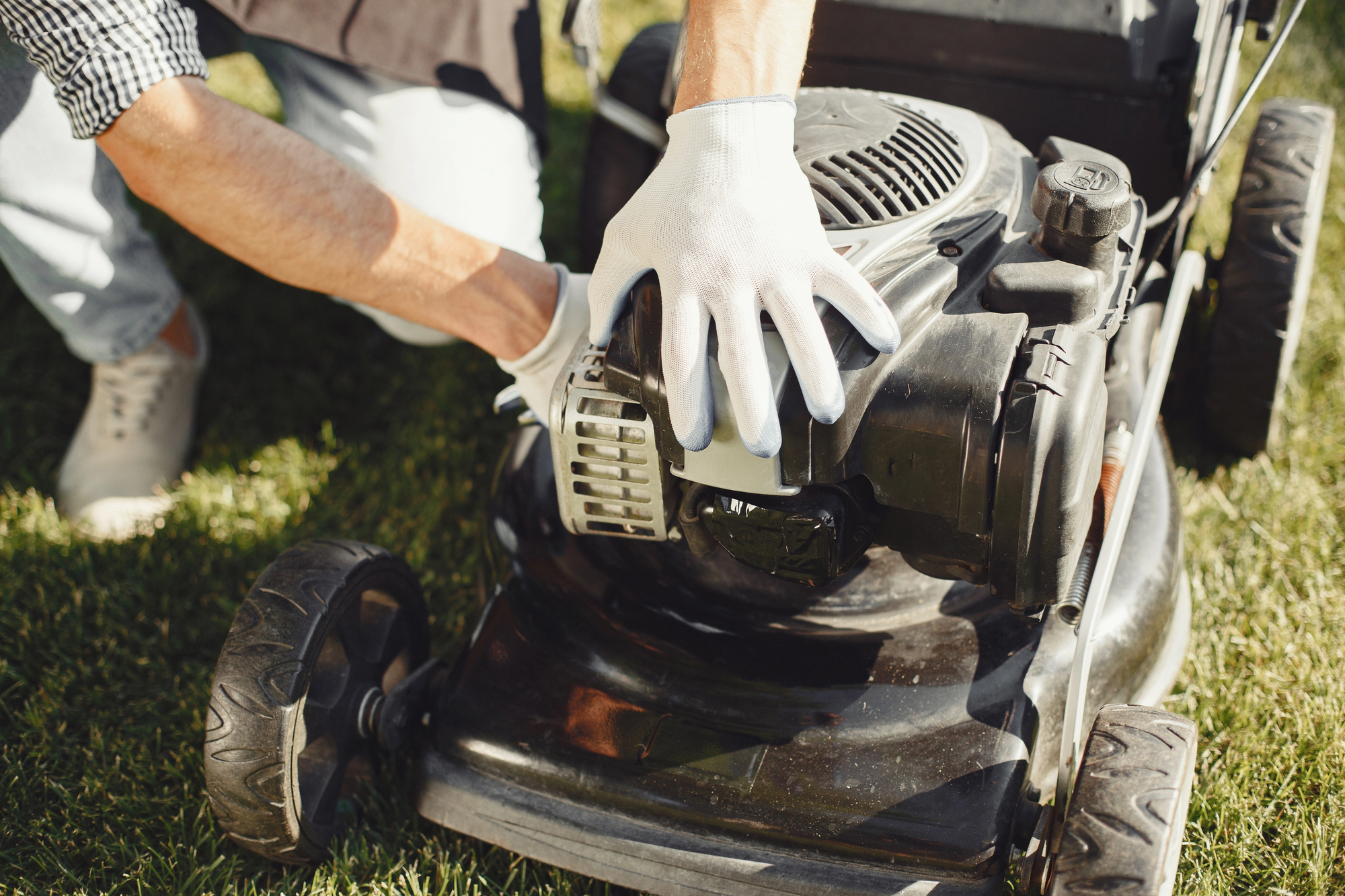 Man repairs lawnmover in a backyard