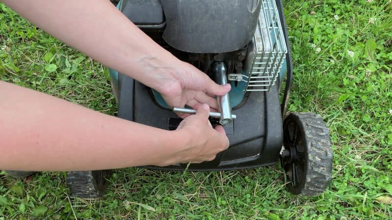 Changing replacing lawn mower spark plug, landscape equipment repair service, process of unscrewing spark plug.